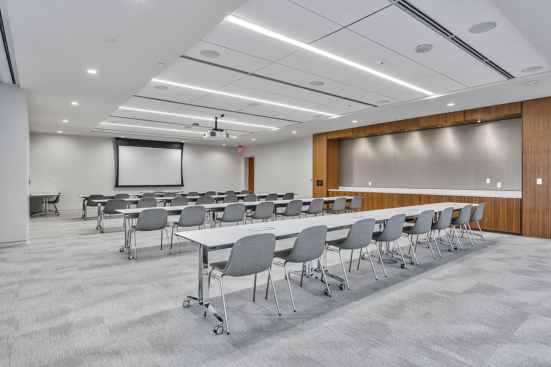 Large meeting room with several tables and chairs facing projector screen