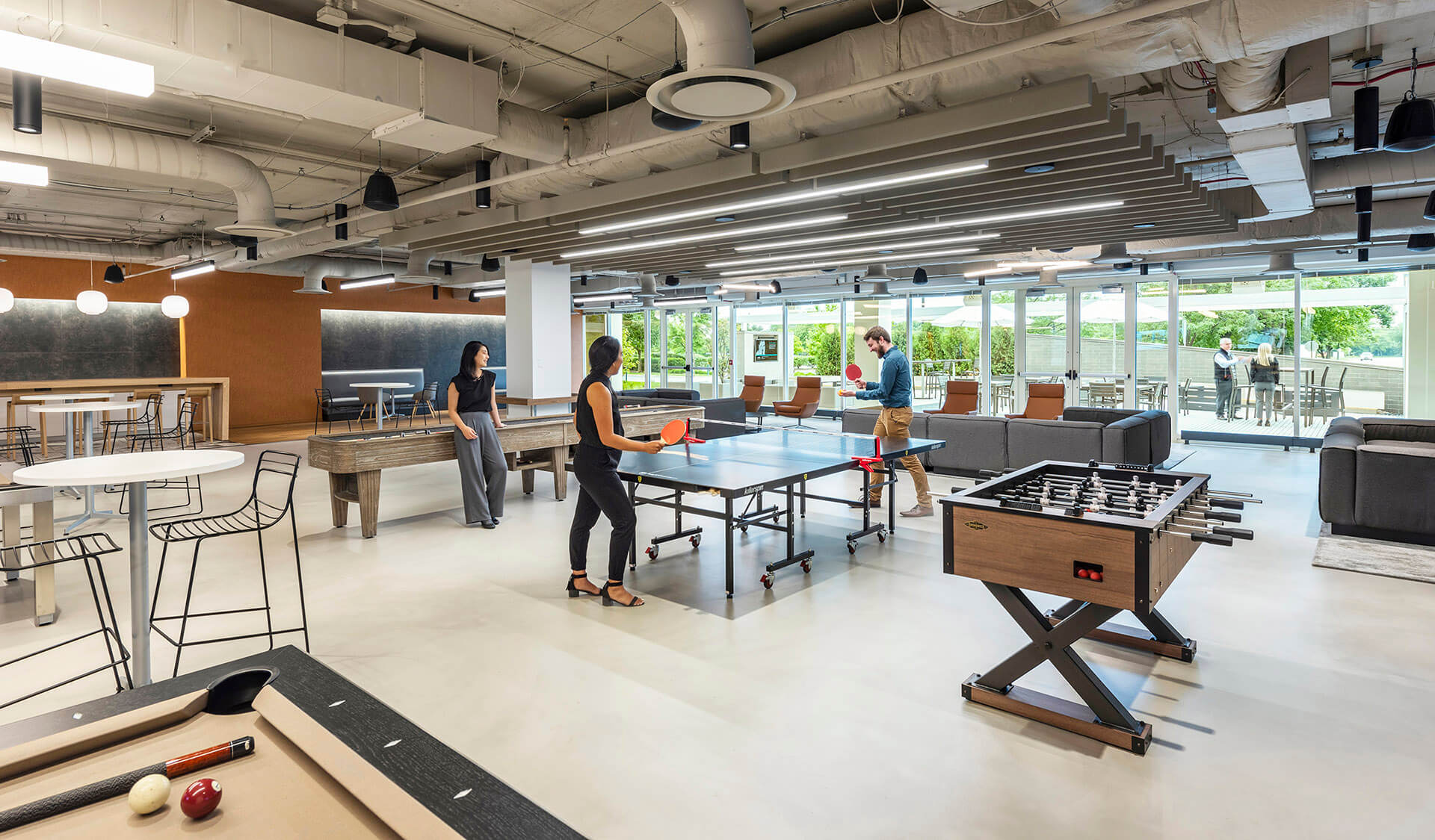 lounge area with foosball, shuffleboard, a pool table and people playing ping pong