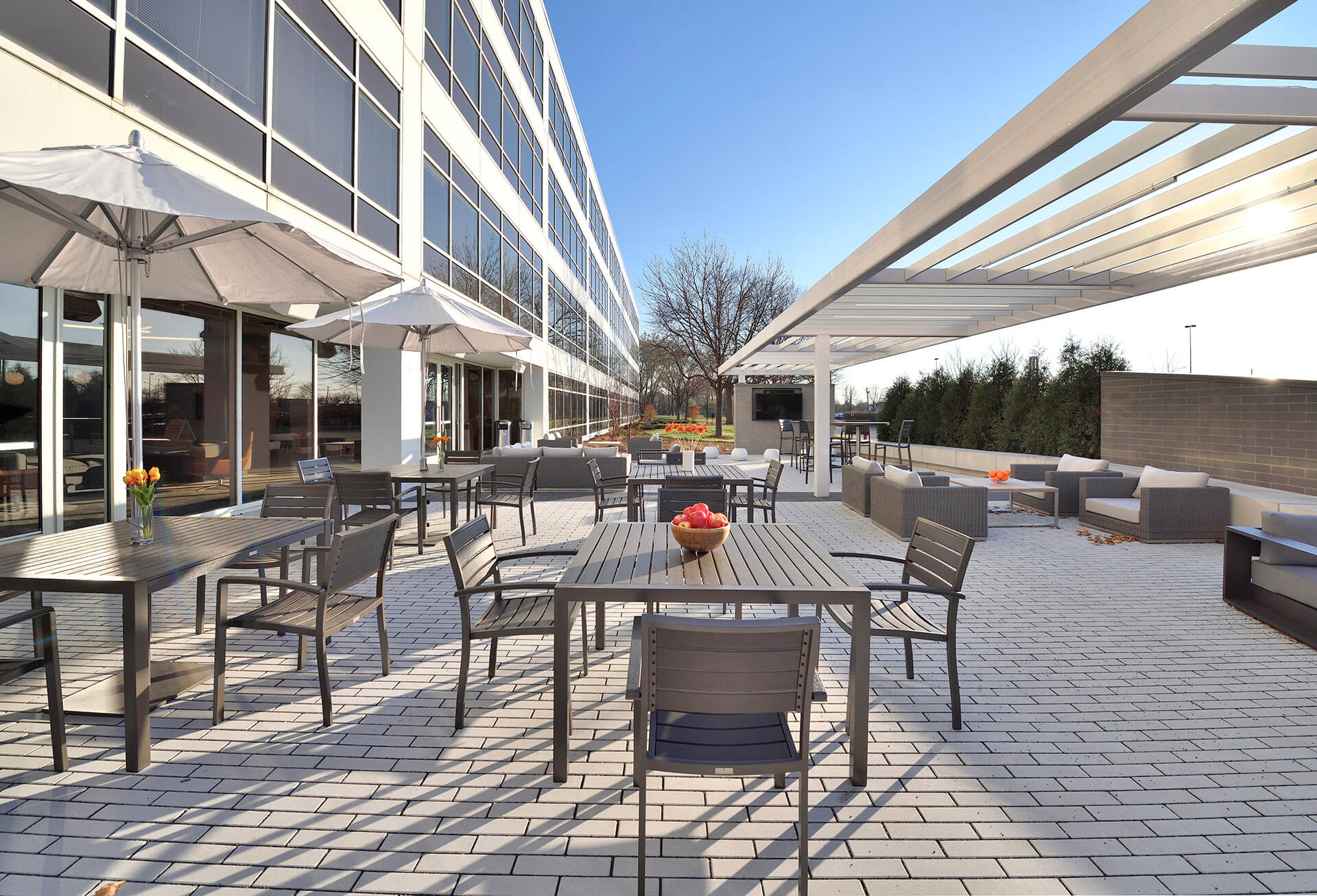 Outdoor patio area with tables, chairs, tv and pergola at Schaumburg Corporate Center